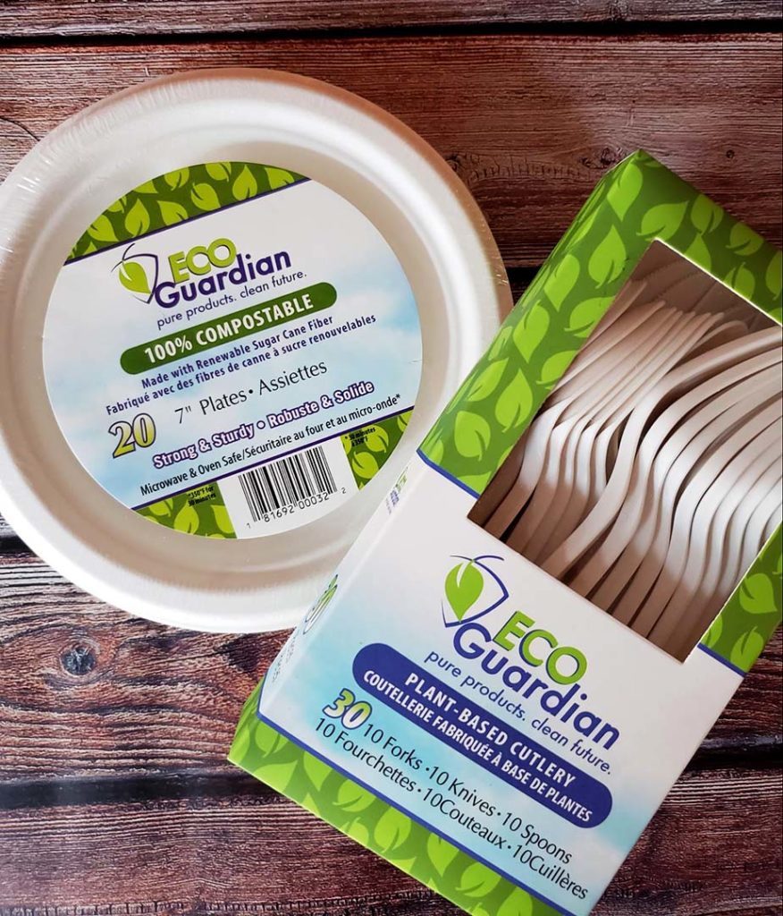 A pack of Eco Guardian compostable plates and box of compostable cutlery on a wooden background.