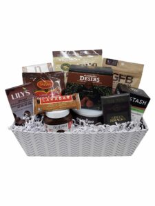 A white rectangular gift basket with black line chevron pattern. In the basket is a variety of chocolate bars and other chocolate-based products.