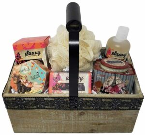 A rectangular wooden gift basket with a black metal handle with a black wooden grip. Inside it are various home spa products.