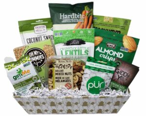 A white and gold Christmas tree rectangular gift basket with various vegan snacks inside, including mixed nuts, chewing gum, mint chocolate bars, dehydrated seaweed snacks and more. The products in the basket are mostly green and/or white, giving it that colour scheme overall.